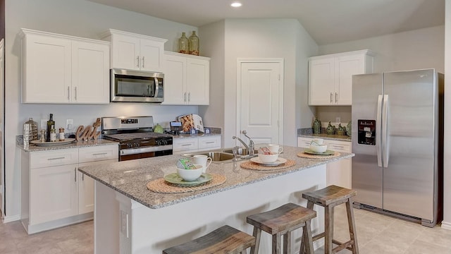 kitchen featuring white cabinetry, stainless steel appliances, an island with sink, and a breakfast bar