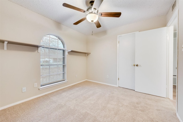 unfurnished bedroom featuring ceiling fan, light colored carpet, and a textured ceiling