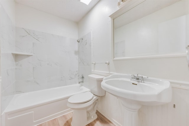 bathroom with tiled shower / bath combo, wood-type flooring, and toilet