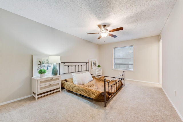 bedroom with ceiling fan, light carpet, and a textured ceiling