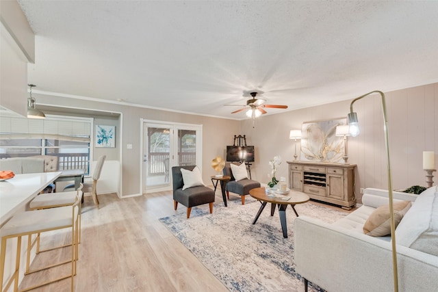 living room featuring crown molding, a textured ceiling, ceiling fan, and light hardwood / wood-style flooring