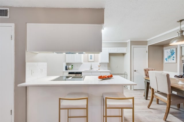 kitchen featuring decorative backsplash, a breakfast bar area, kitchen peninsula, and white cabinets