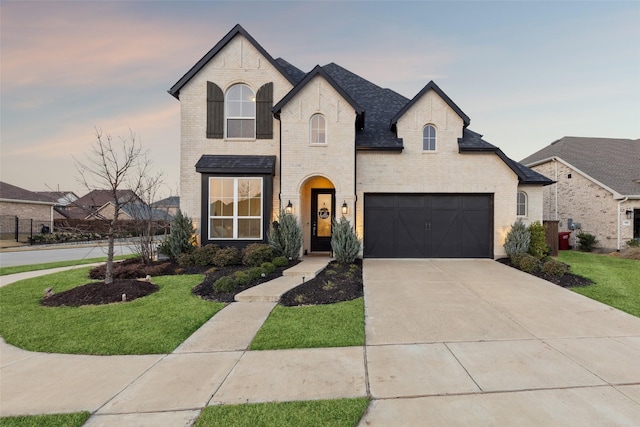 french country style house with a garage and a lawn