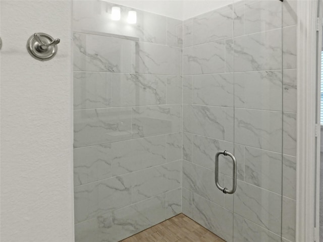 bathroom with hardwood / wood-style floors and a shower with shower door