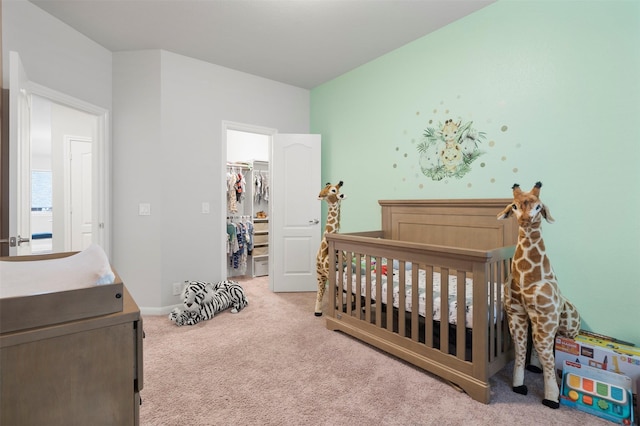 carpeted bedroom with a walk in closet, a closet, and a crib