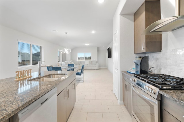 kitchen featuring sink, stainless steel range with gas stovetop, white dishwasher, light stone countertops, and wall chimney range hood