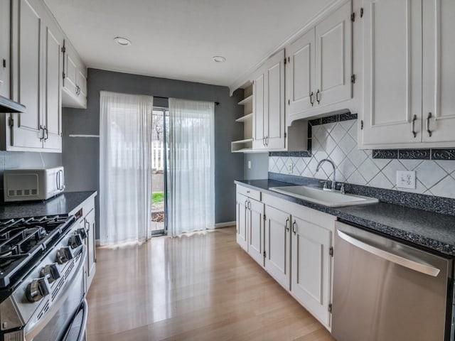 kitchen with backsplash, stainless steel appliances, sink, and white cabinets