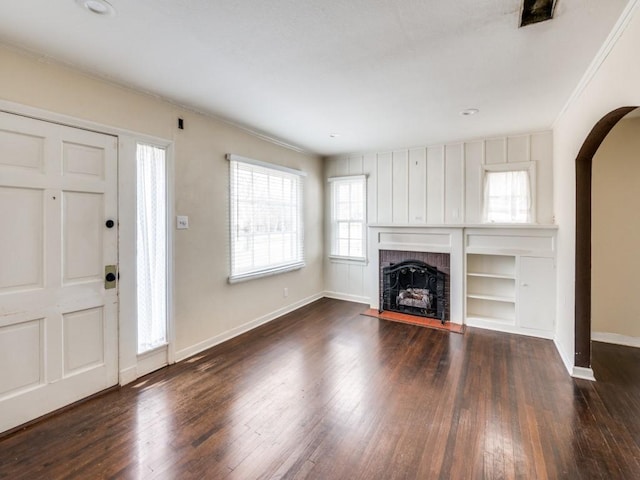 unfurnished living room with a brick fireplace, crown molding, and dark hardwood / wood-style floors