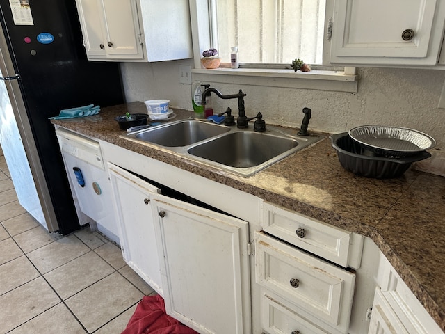 kitchen with sink, light tile patterned floors, dishwasher, and white cabinets