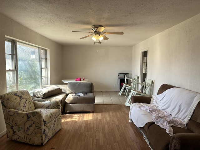 living room with ceiling fan, hardwood / wood-style floors, and a textured ceiling