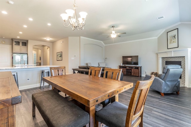 dining room featuring a tile fireplace, vaulted ceiling, dark hardwood / wood-style floors, ceiling fan, and crown molding