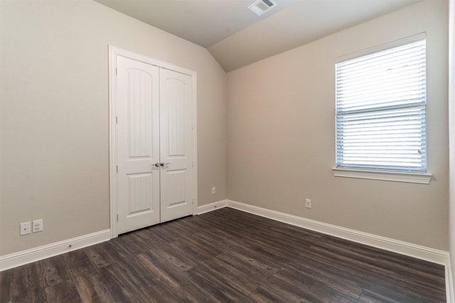 unfurnished bedroom with a closet, vaulted ceiling, and dark hardwood / wood-style floors