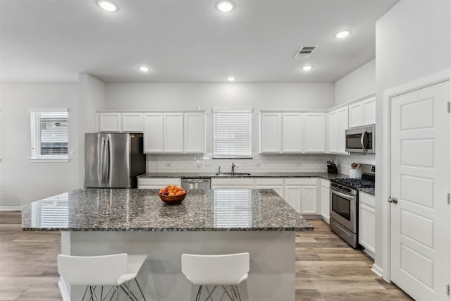 kitchen featuring stainless steel appliances, a center island, sink, and white cabinets