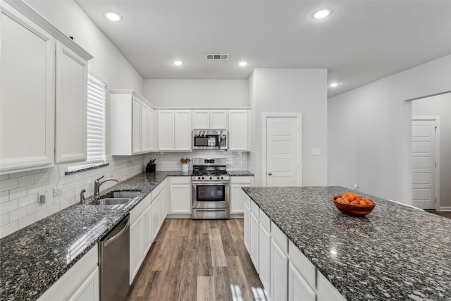 kitchen with white cabinetry, sink, stainless steel appliances, and dark stone countertops