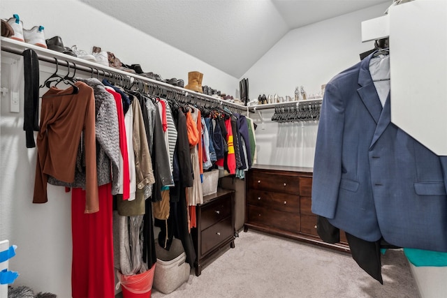 walk in closet featuring light colored carpet and vaulted ceiling