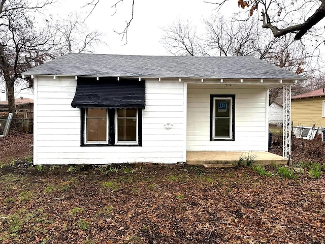 view of front facade with fence and roof with shingles