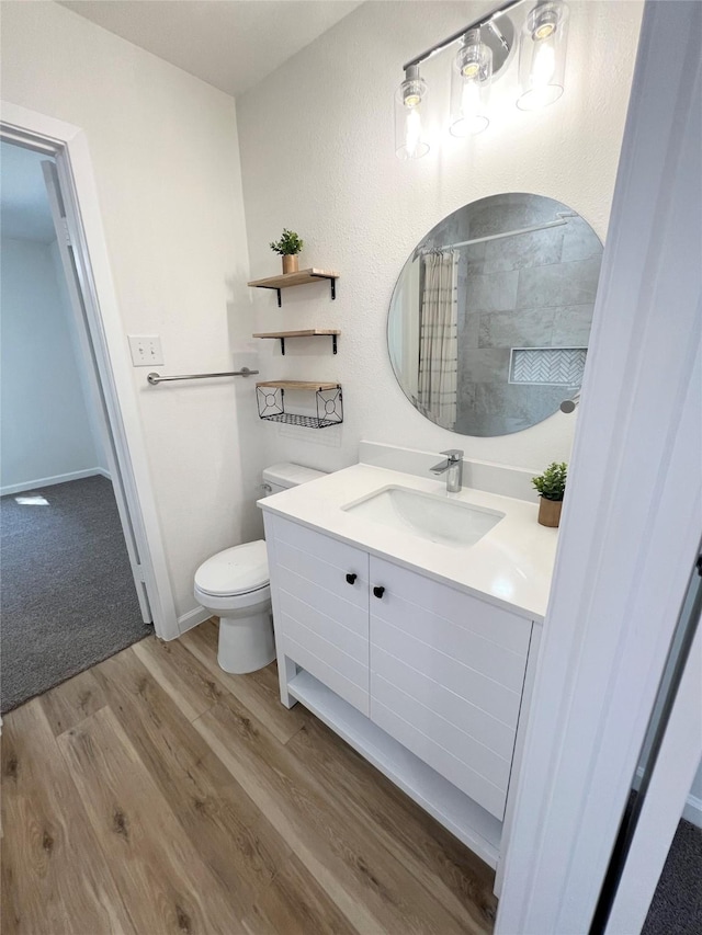 bathroom with hardwood / wood-style flooring, vanity, curtained shower, and toilet