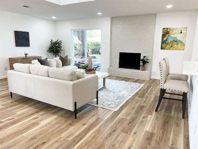 living room featuring a brick fireplace and wood-type flooring