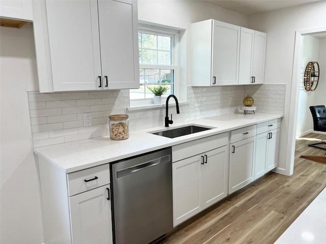 kitchen with sink, white cabinets, stainless steel dishwasher, light stone counters, and light hardwood / wood-style flooring