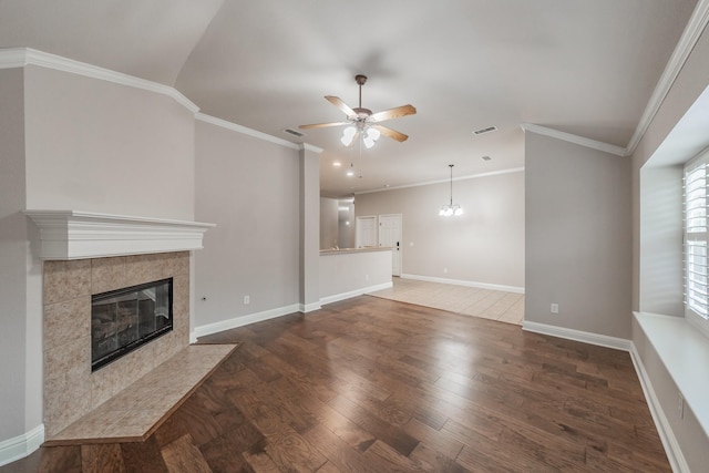 unfurnished living room featuring crown molding, ceiling fan, dark hardwood / wood-style floors, and a tiled fireplace