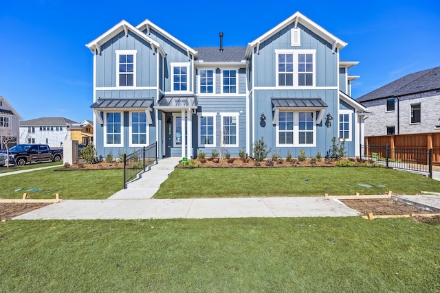 view of front of property featuring a standing seam roof, a front lawn, board and batten siding, and fence