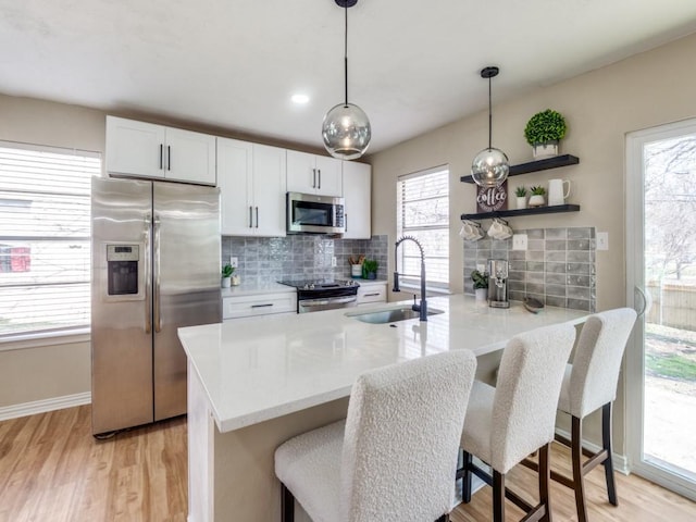 kitchen featuring appliances with stainless steel finishes, pendant lighting, sink, white cabinets, and backsplash