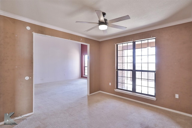 empty room featuring a textured ceiling, ornamental molding, light colored carpet, and ceiling fan