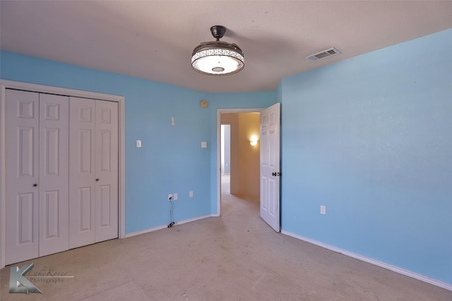 unfurnished bedroom with light colored carpet and a closet