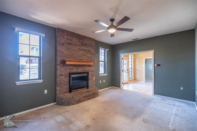 unfurnished living room with ceiling fan, plenty of natural light, a fireplace, and light carpet