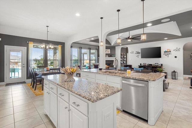 kitchen featuring decorative light fixtures, stainless steel dishwasher, open floor plan, a sink, and an island with sink