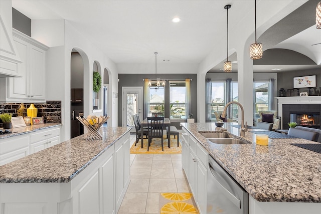 kitchen featuring a sink, a kitchen island with sink, dishwasher, and decorative light fixtures