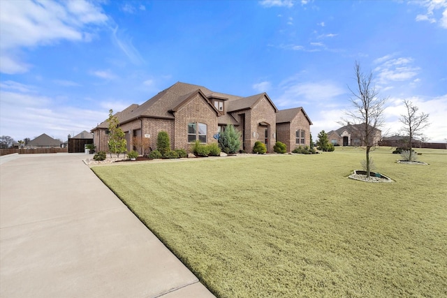 french country inspired facade with concrete driveway, brick siding, a front lawn, and roof with shingles