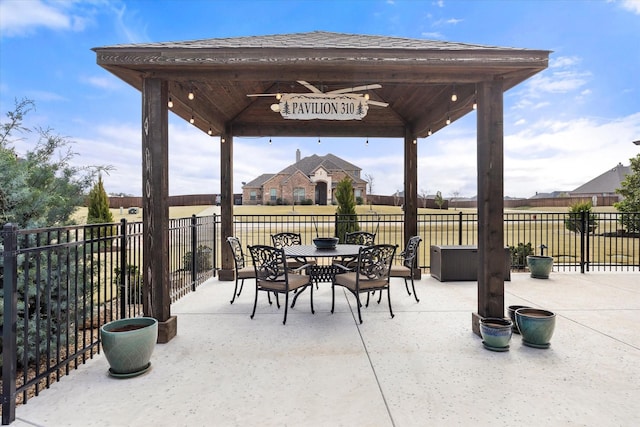 view of patio with outdoor dining area, fence, and a gazebo