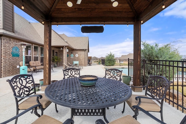 view of patio featuring outdoor dining space, fence, and a gazebo