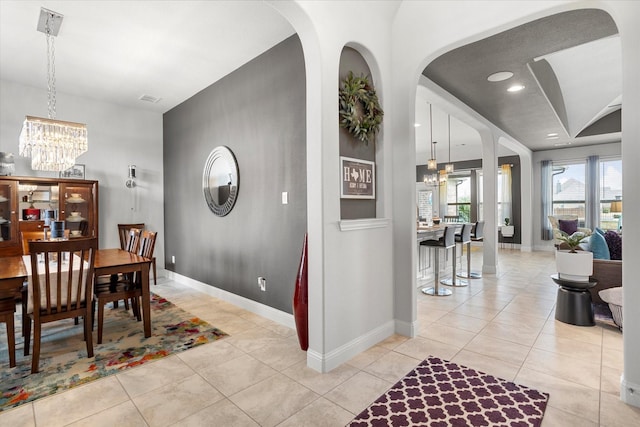 dining space with baseboards, light tile patterned floors, and a notable chandelier