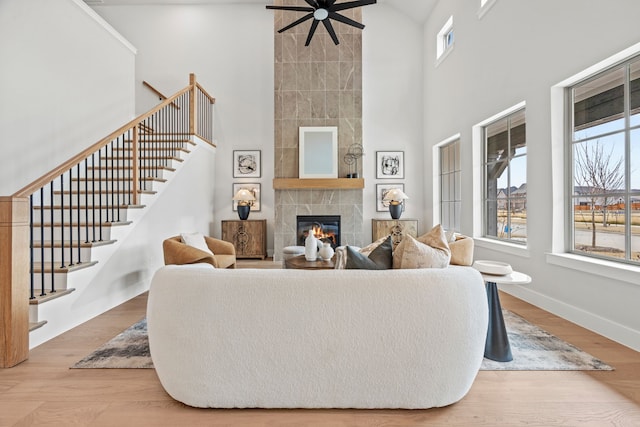 living room with hardwood / wood-style flooring, a towering ceiling, and a tiled fireplace