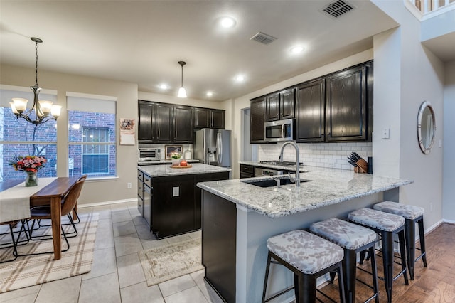 kitchen featuring stainless steel appliances, a kitchen island, sink, and decorative light fixtures