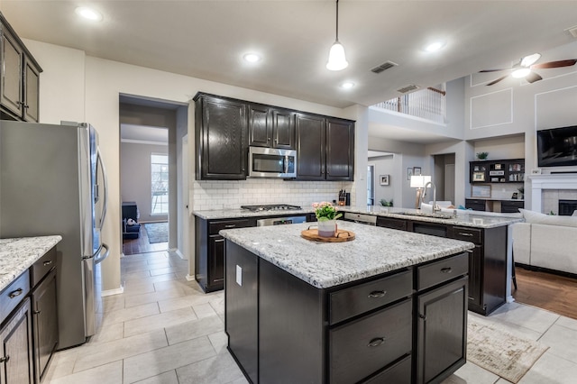 kitchen featuring stainless steel appliances, hanging light fixtures, a center island, and sink