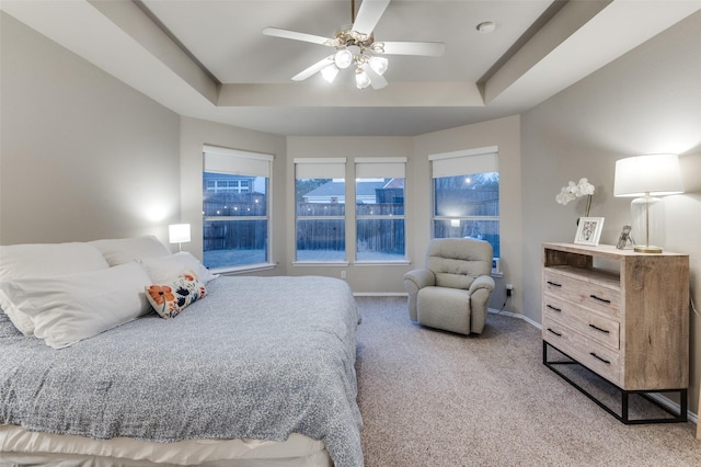 bedroom featuring ceiling fan, a tray ceiling, and carpet floors