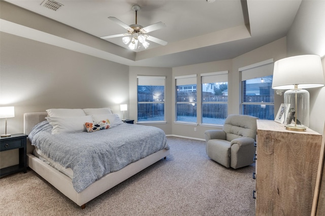 bedroom featuring a raised ceiling, ceiling fan, and carpet