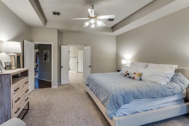 carpeted bedroom with ceiling fan and a tray ceiling