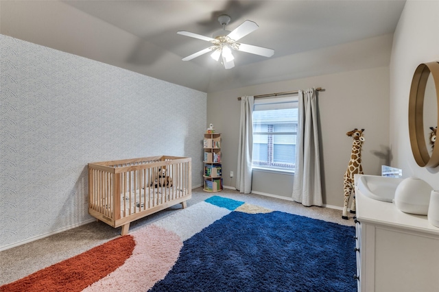 carpeted bedroom with a nursery area and ceiling fan