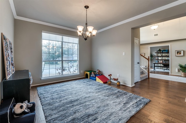 recreation room featuring ornamental molding, dark hardwood / wood-style floors, and a chandelier