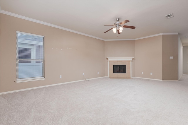 unfurnished living room with a tiled fireplace, crown molding, light carpet, and ceiling fan