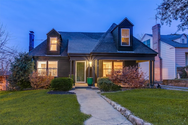 cape cod house featuring a lawn