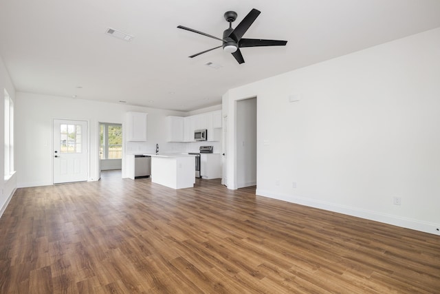 unfurnished living room with sink, hardwood / wood-style flooring, and ceiling fan