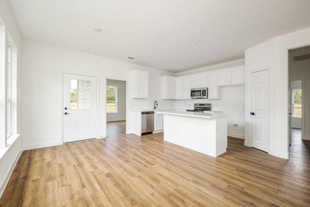 kitchen featuring stainless steel appliances, a center island, white cabinets, and light hardwood / wood-style flooring