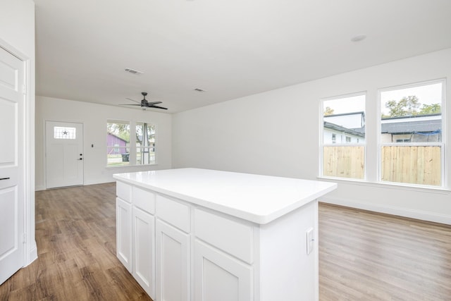 kitchen featuring white cabinetry, ceiling fan, a center island, and light hardwood / wood-style floors