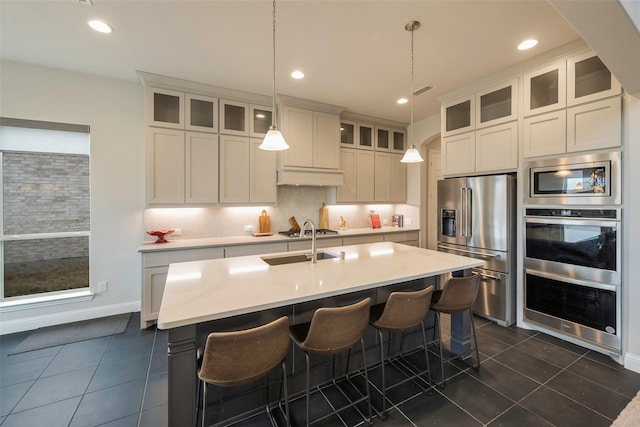 2402 Topaz Dr, Rockwall, TX 75087 - kitchen featuring appliances with stainless steel finishes, dark tile patterned flooring, an island with sink, and hanging light fixtures