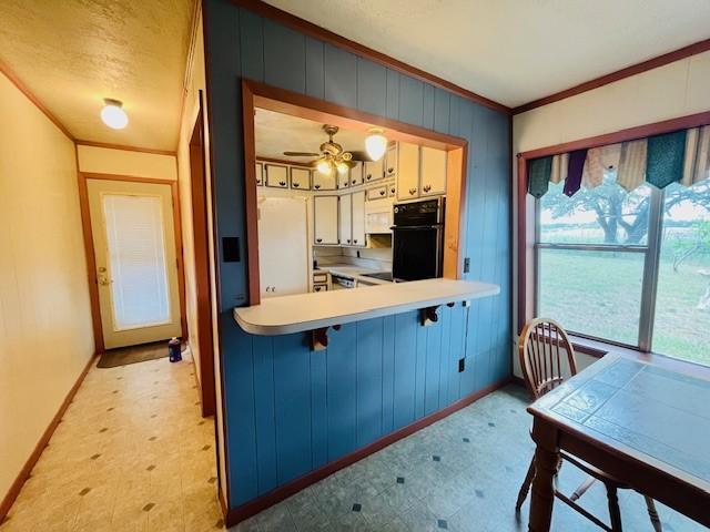 kitchen with pendant lighting, white cabinetry, ornamental molding, kitchen peninsula, and white fridge